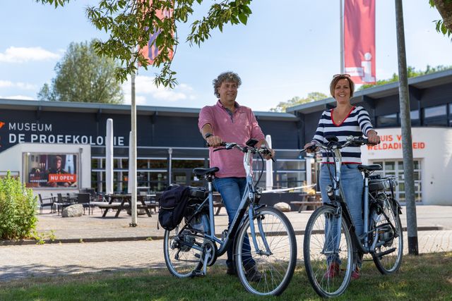 Twee mensen met fiets voor museum De Proefkolonie in Frederiksoord