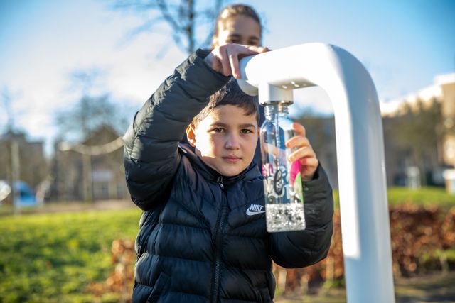 Foto van een jongetje die water tapt bij watertappunt Boschveld