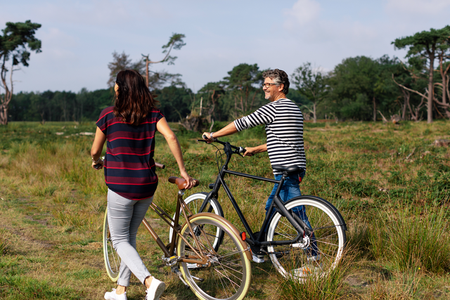 Ein Paar steigt für eine kleine Pause in der Natur von Drenthe vom Fahrrad.