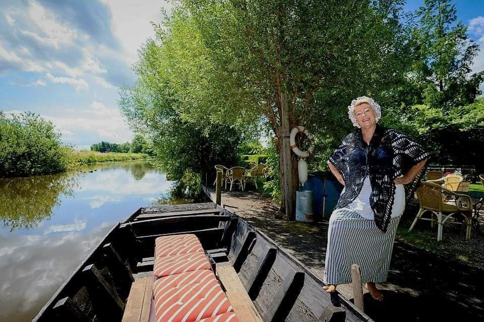 Vrouw in Nederlandse klederdracht bij een bootje aan het water