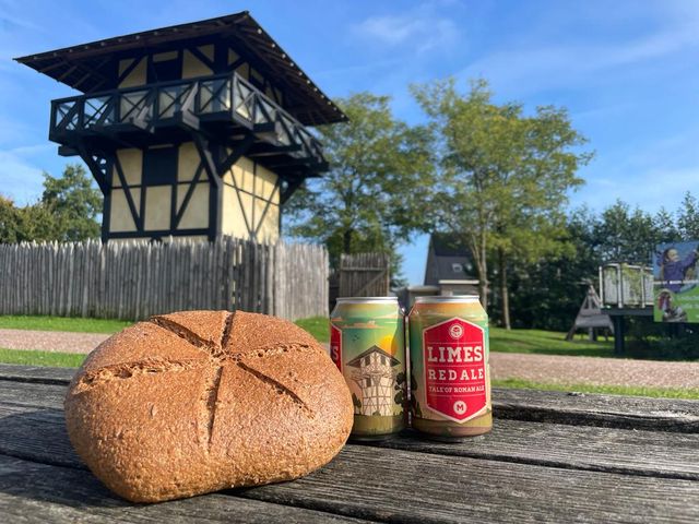 Blikje bier en een brood op een picknicktafel. Op de achtergrond de wachttoren bij Castellum Hoge Woerd.