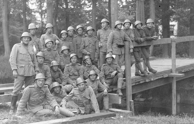Groep van 23 soldaten op een brug in zwart-wit.