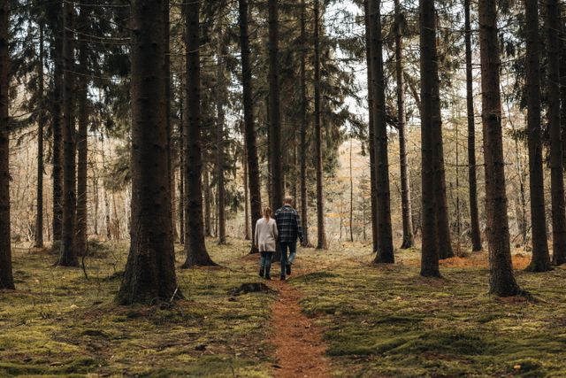 Een man en een vrouw wandelen door een bos met herfstkleuren.