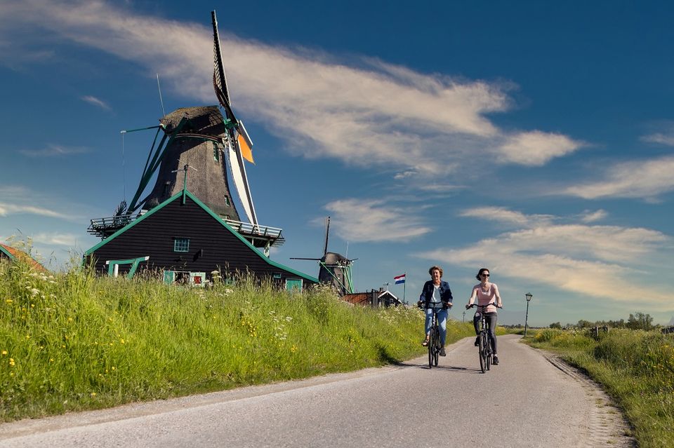 Twee fietsers fietsen langs een molen op de Zaanse Schans