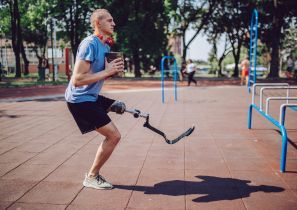 Een man in sportkleding met een beenprothese staat op een pleintje.