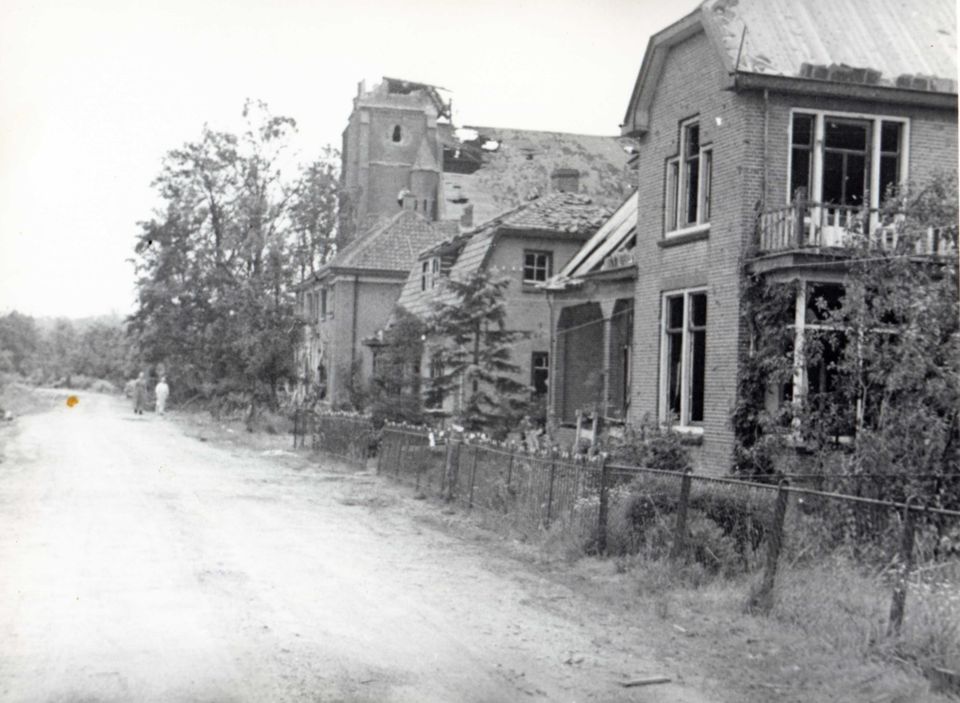 De zwaar beschadigde huizen aan de oostkant van de Kerkstraat met de katholieke kerk.