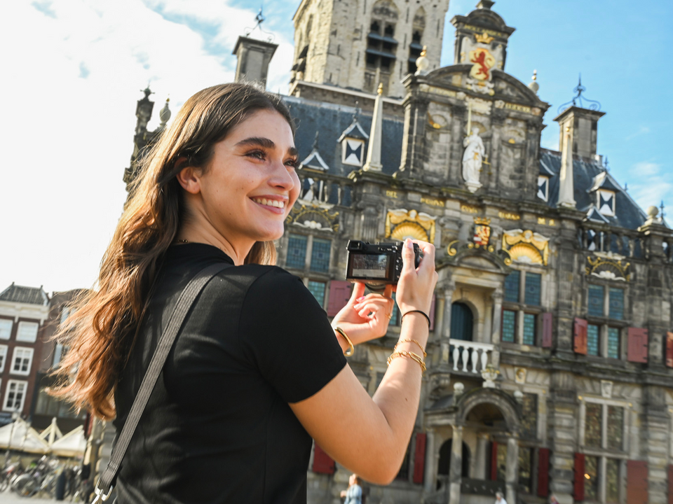 Dame maakt een foto van het stadhuis in Delft