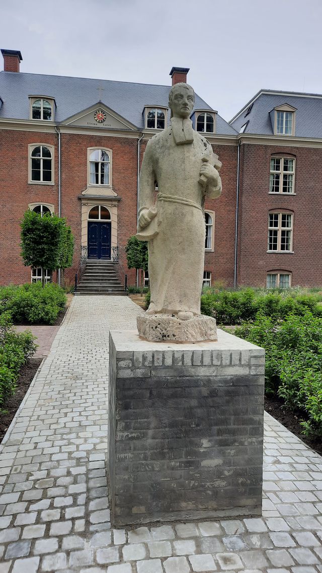 voorgevel hoofdgebouw met beeld van de stichter van het seminarie op de voorgrond.