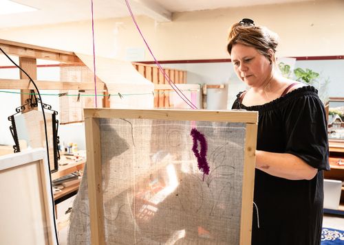 Een kunstenares aan het werk met textiel in haar Atelier