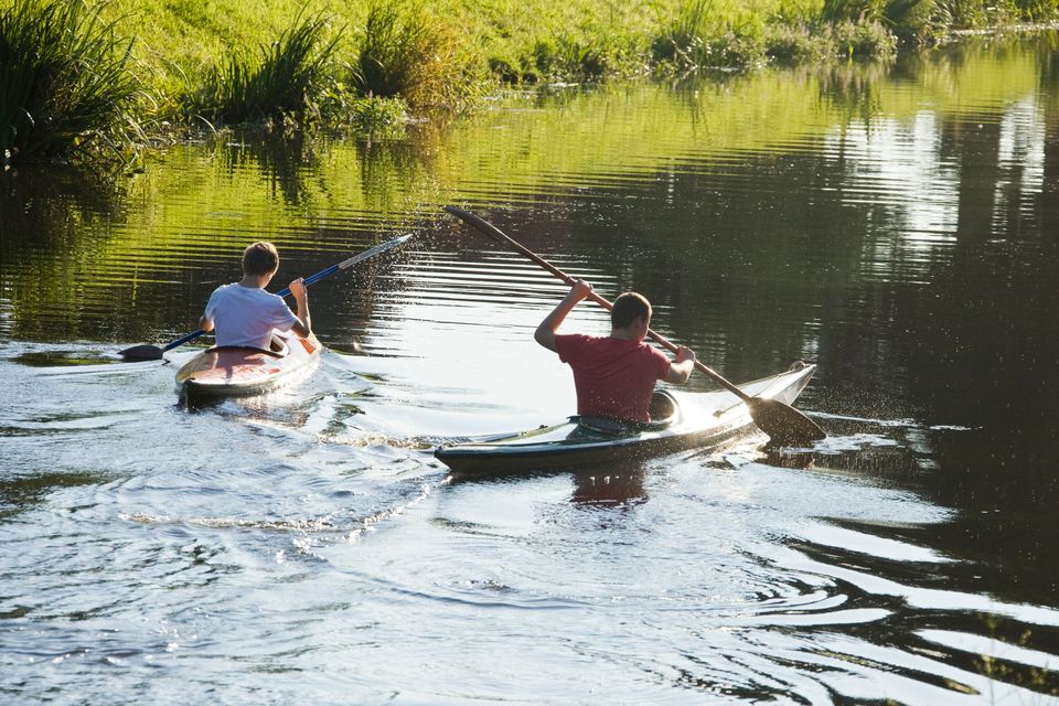 Twee jongens varen met hun kajak door het water.