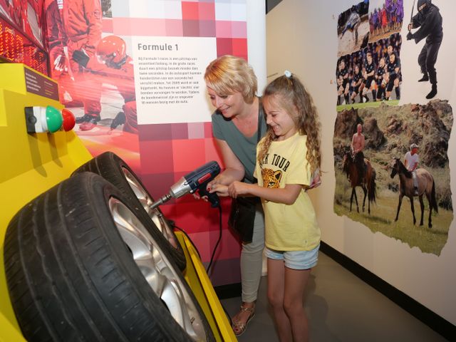 Moeder en dochter zijn samen een Formule 1 band aan het vervangen in het museum.