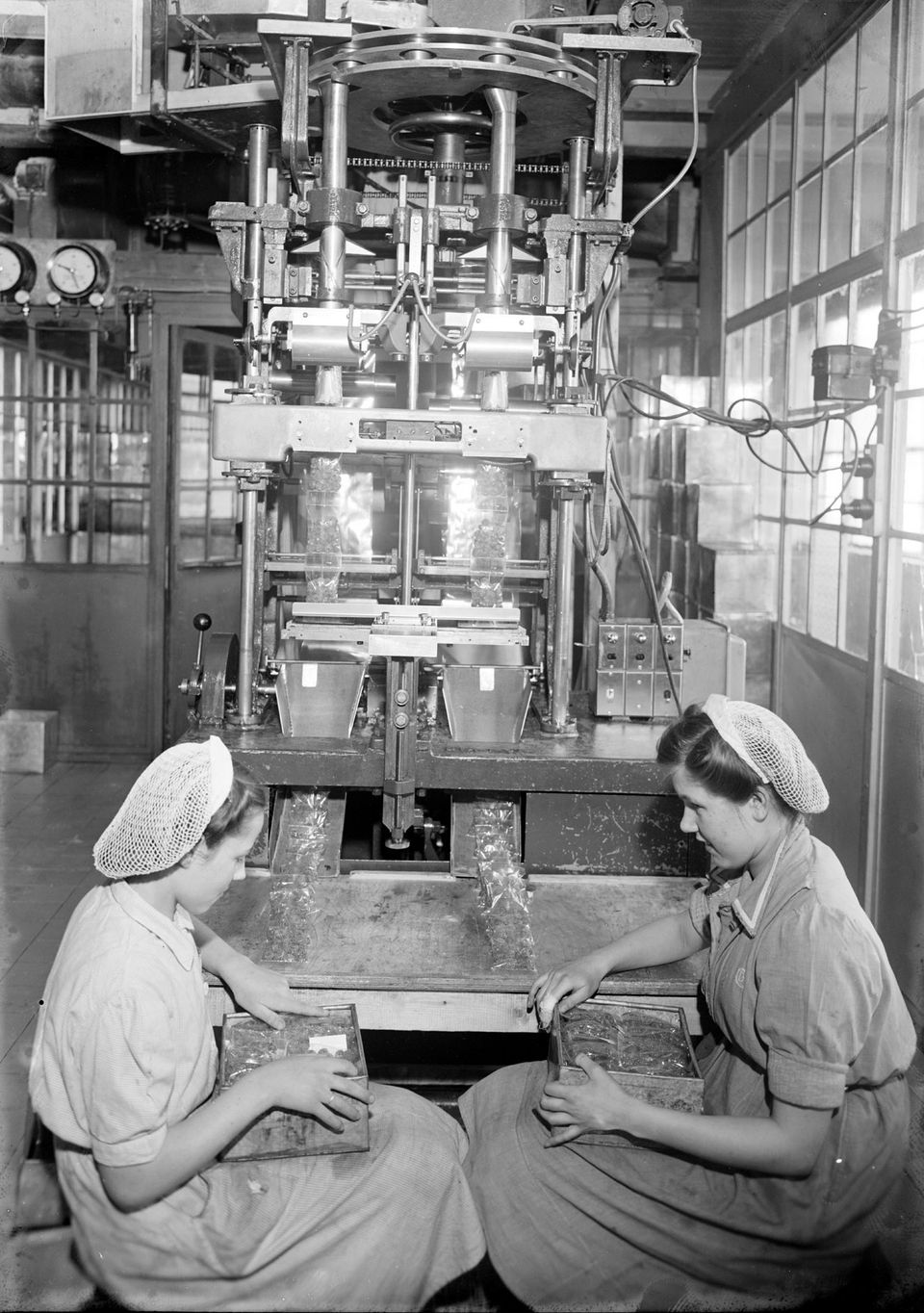 Historische foto van twee vrouwen in een fabriek.