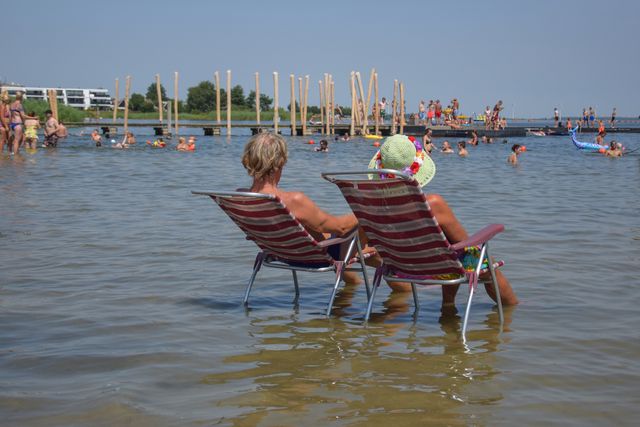 Man en vrouw zitten op stoelen in het water van het strand Woldstrand in Zeewolde, Flevoland