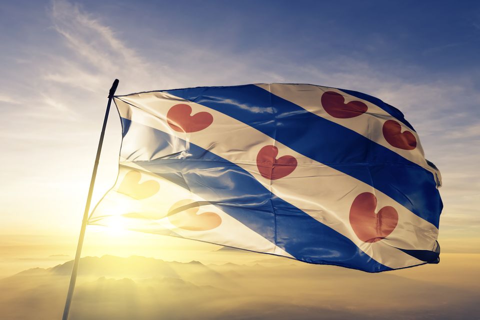 De Friese vlag waaien in de avondzon.