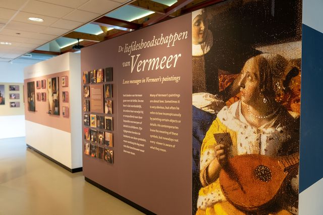 Binnen bij het Vermeer Centrum Delft met een beschrijving en poster van de liefdesboodschappen van Vermeer
