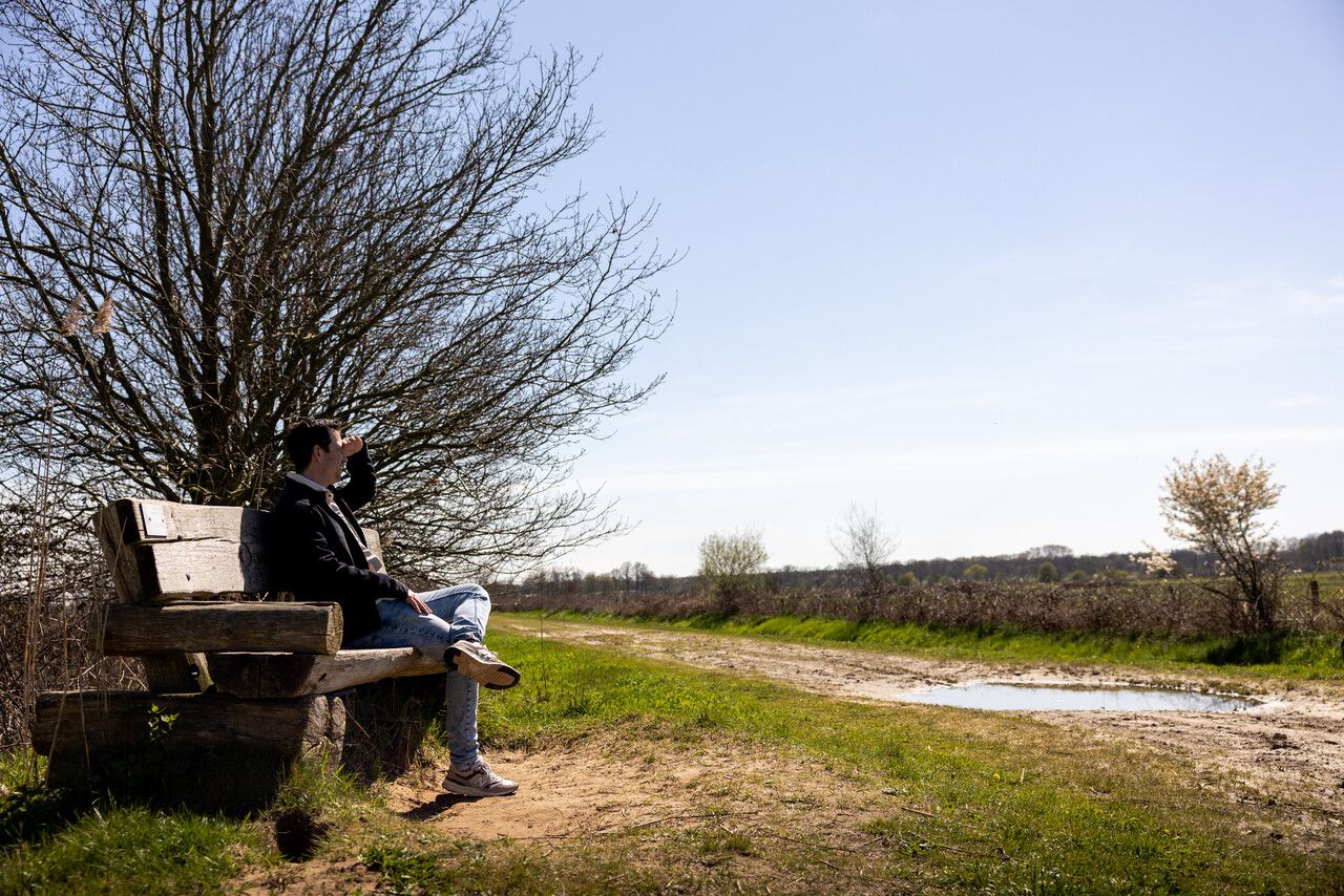Een man op een bankje kijken naar het boerenland