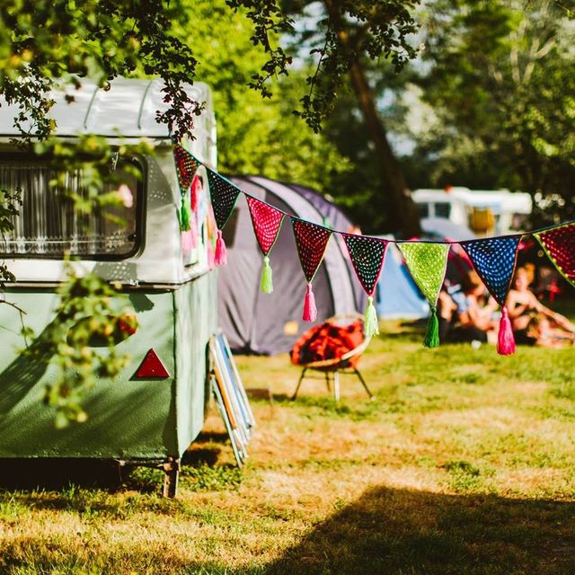 Kleurrijke foto van een camping met vlaggetjes aan de caravan.