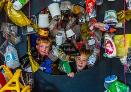 twee kinderen kruipen door een gordijn van plastic verpakkingen