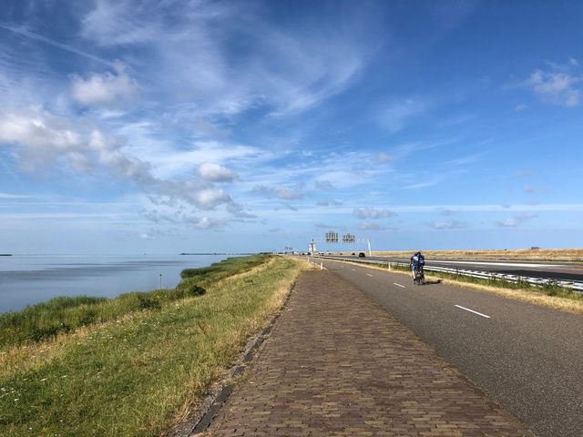 De Afsluitdijk, met daarnaast het fietspad me een fietser.