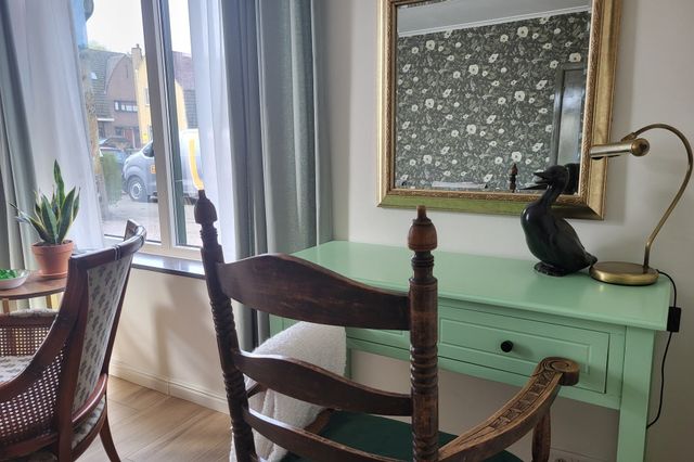 Groen bureau met houten stoel in een woonkamer van Logement Hartsuiker.
