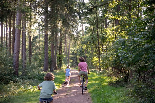 Vader met dochter en zoon fietsen door het bos.