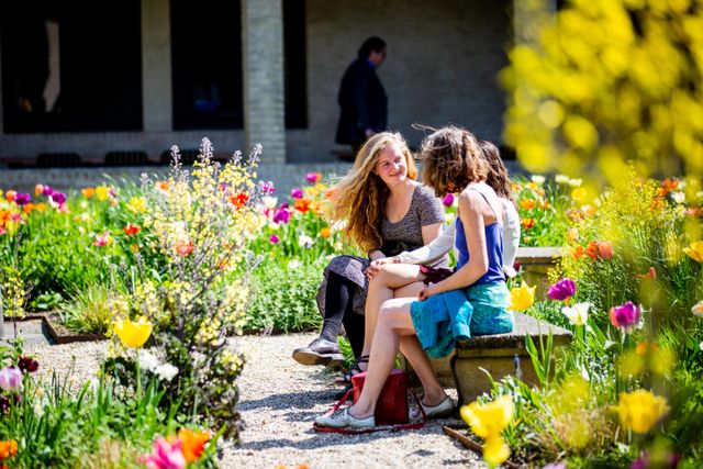 Drie vrouwen zitten op een bankje in de bloemrijke binnentuin van Buitenplaats Doornburgh.