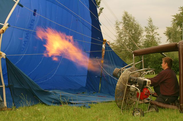 Een ballon die met hete lucht word gevuld door een man.