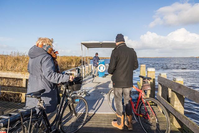 een stel stapt op de pont met fietsen op een zonnige herfstdag