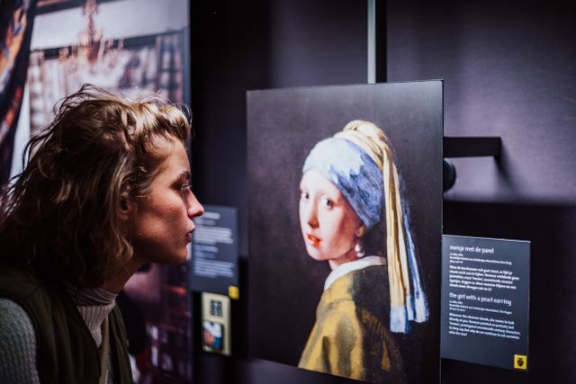 Dame kijkend naar replica van het Meisje met de Parel in het Vermeer Centrum Delft