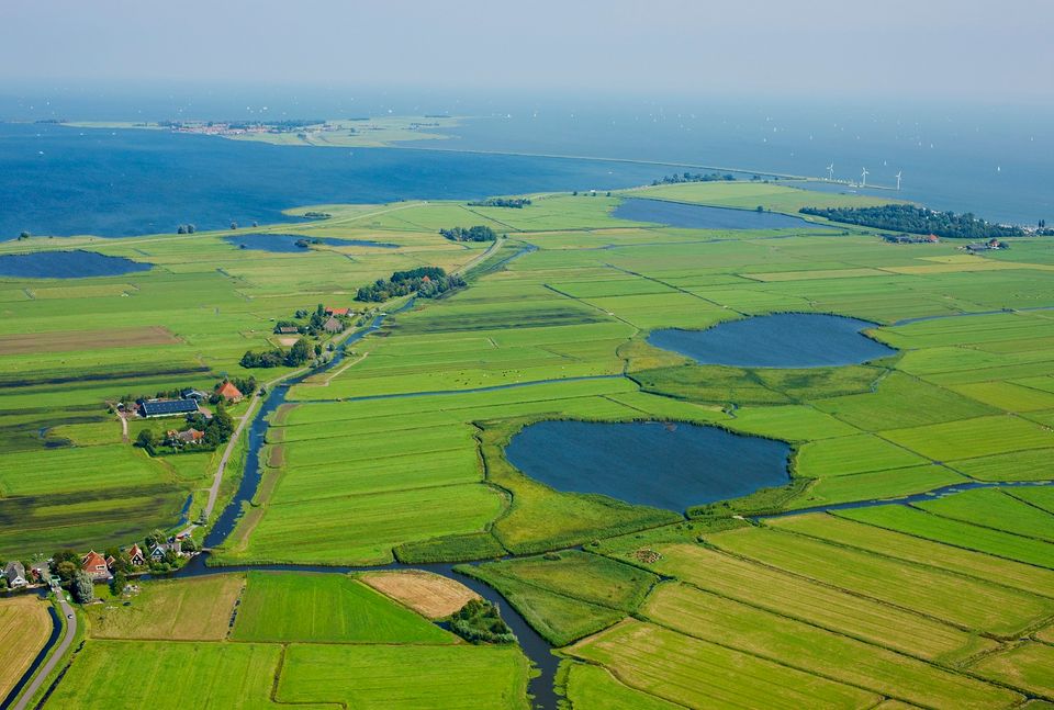 Luchtfoto van het dorp Zuiderwoude met Marken op de achtergrond gemaakt in de Noord-Hollandse regio Laag Holland.