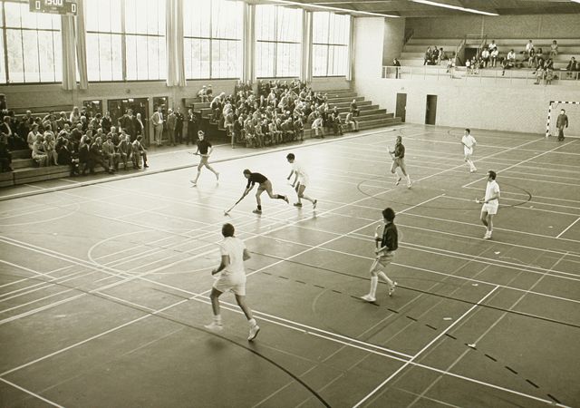 Zwart wit foto van sporthal met sportende mensen.