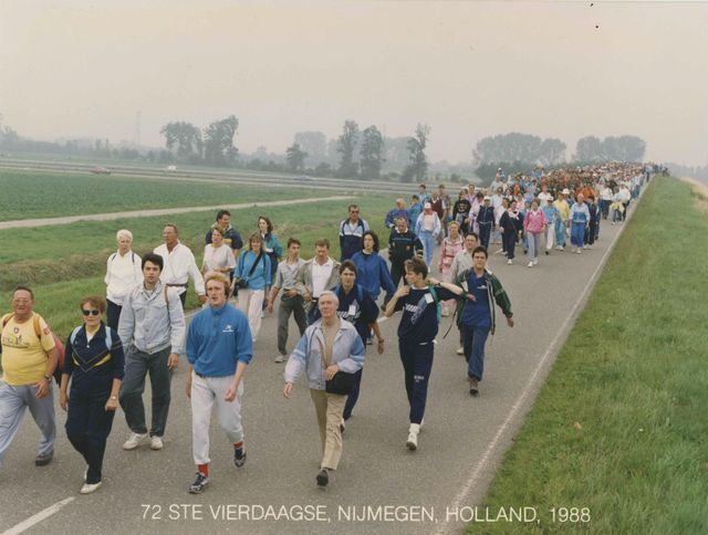 Een Zwitserse deelnemer (SUI) die de 100 km van Biel gelopen heeft (links), individuele deelnemers, voornamelijk in trainingspakken, en een detachement Nederlandse militairen op het parcours van 40 km onderweg tussen Valburg en Slijk-Ewijk op de eerste dag van de 72e Vierdaagse.