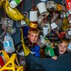 twee kinderen kruipen door een gordijn van plastic verpakkingen