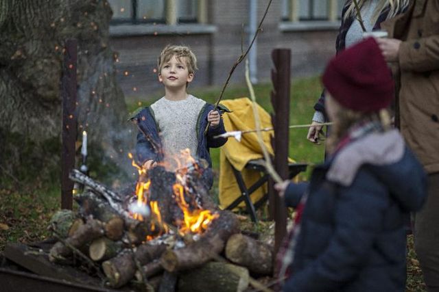 Ein Junge und ein Mädchen werden am Lagerfeuer warm und braten Marshmellows