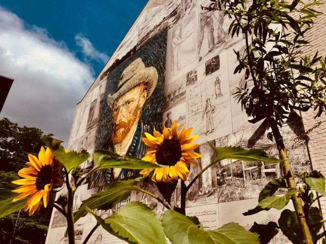 Etten-Leur. Wand met grote afbeelding van Van Gogh. Zonnebloemen onder de wand op de foto