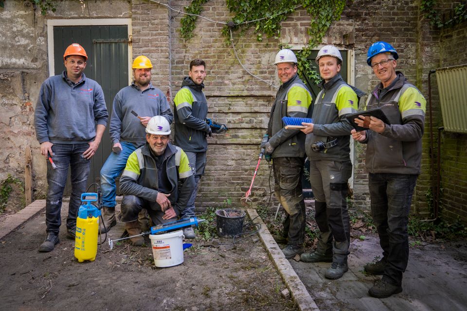 Foto van metselaars die opgeleid worden door op een oude Bossche muur te metselen.