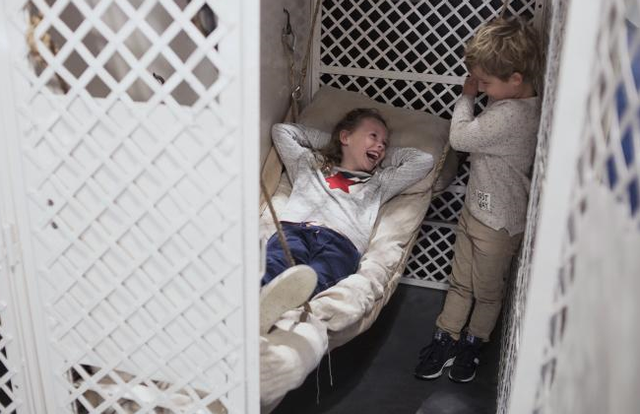 een jongen en een meisje staan in een voormalige cel in het Gevangenismuseum in Veenhuizen. Het meisje probeert het bedje en ze hebben dikke lol.
