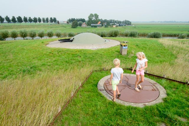 Bovenop Fort bij Spijkerboor staan een jonge en een meisje bij het kanon, met uitzicht op de Beemsterringdijk.