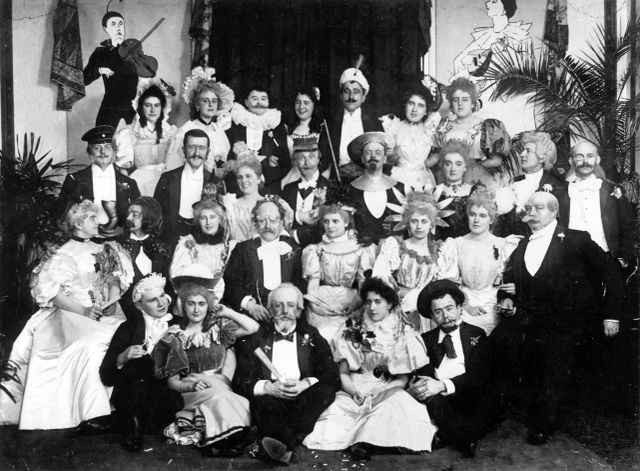 Groepsfoto van het gekostumeerd carnavalesk diner op 15 februari 1896 in De Zwarte Arend. Uit de handtekeningen achterop de foto blijkt dat diverse leden van de Raad van XI en de nieuwe President van de Oeteldonksche Club, Eduard van de Mortel, eveneens aanwezig waren 