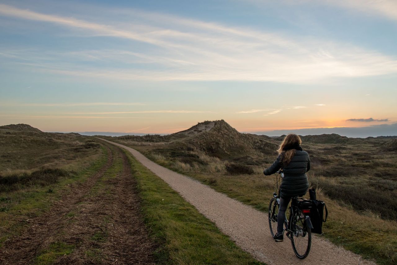 Vrouw fietst op fietspad in duinen Vlieland