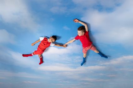 Twee kinderen die lijken te zweven tegen een plafond van wolken