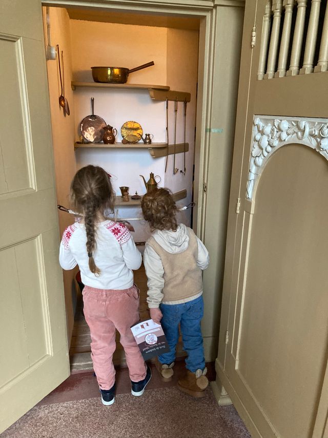 Twee kindjes doen de muizenspeurtocht in Slot Zuylen en kijken in een kast.