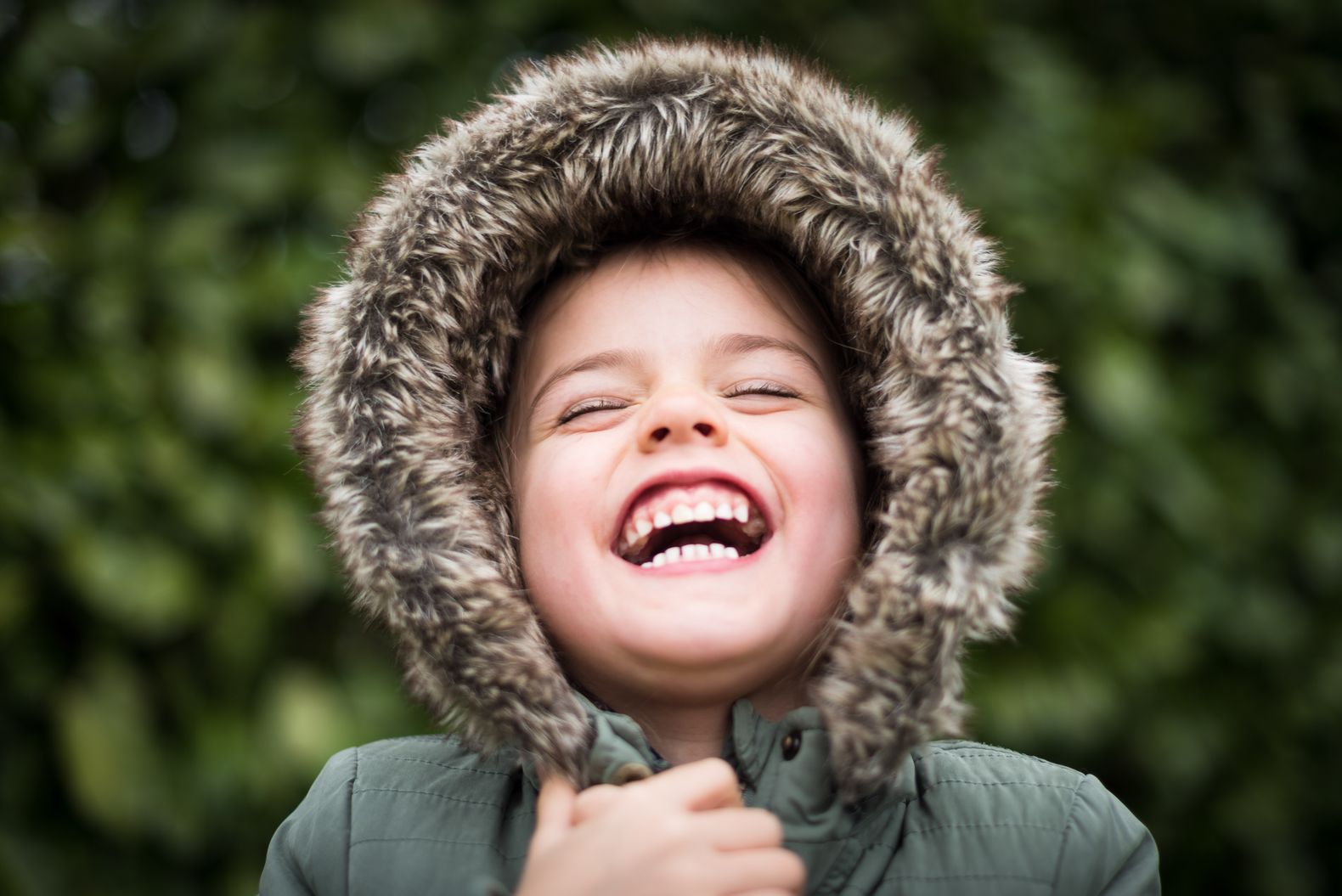 Een kind met een winterjas die blij lacht.