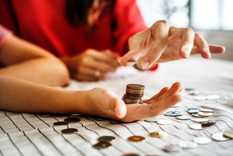 Two people counting coins on a table.