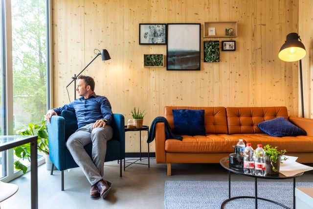 Een man kijkt naar buiten vanuit een stoel in een woonkamer van een Startblock woning in Flevoland