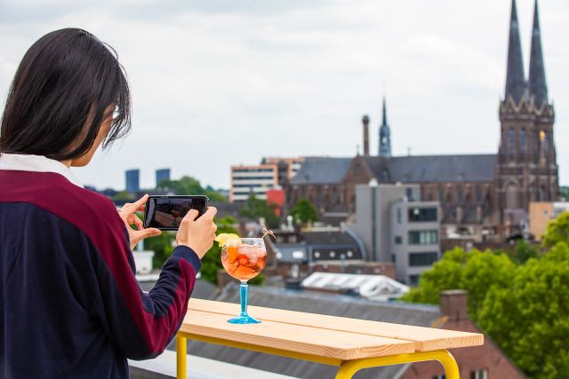 Een vrouw die een foto maakt van een drankje bij Doloris Tilburg.