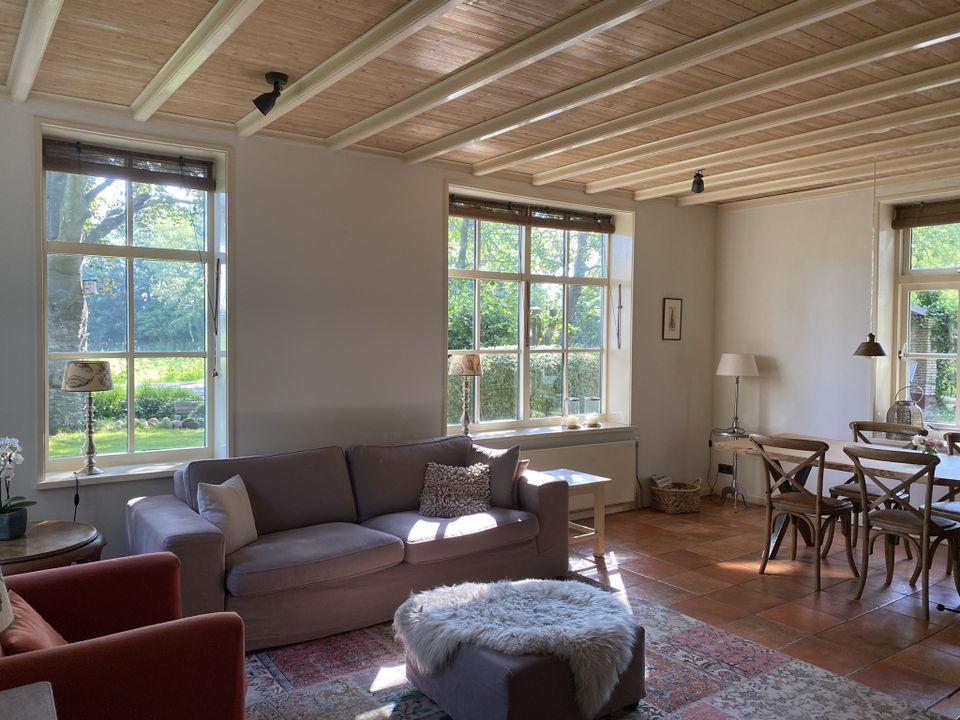 De L-vormige woonkamer met zithoek, eethoek, houtkachel en vrij uitzicht over de Onner Es