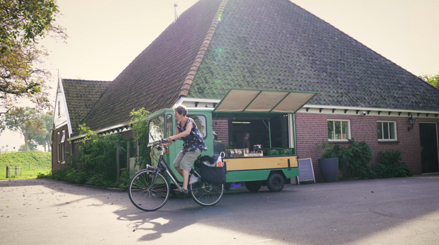 Fietser fiets weg met verse streekproducten van De Proeftuin in De Beemster.