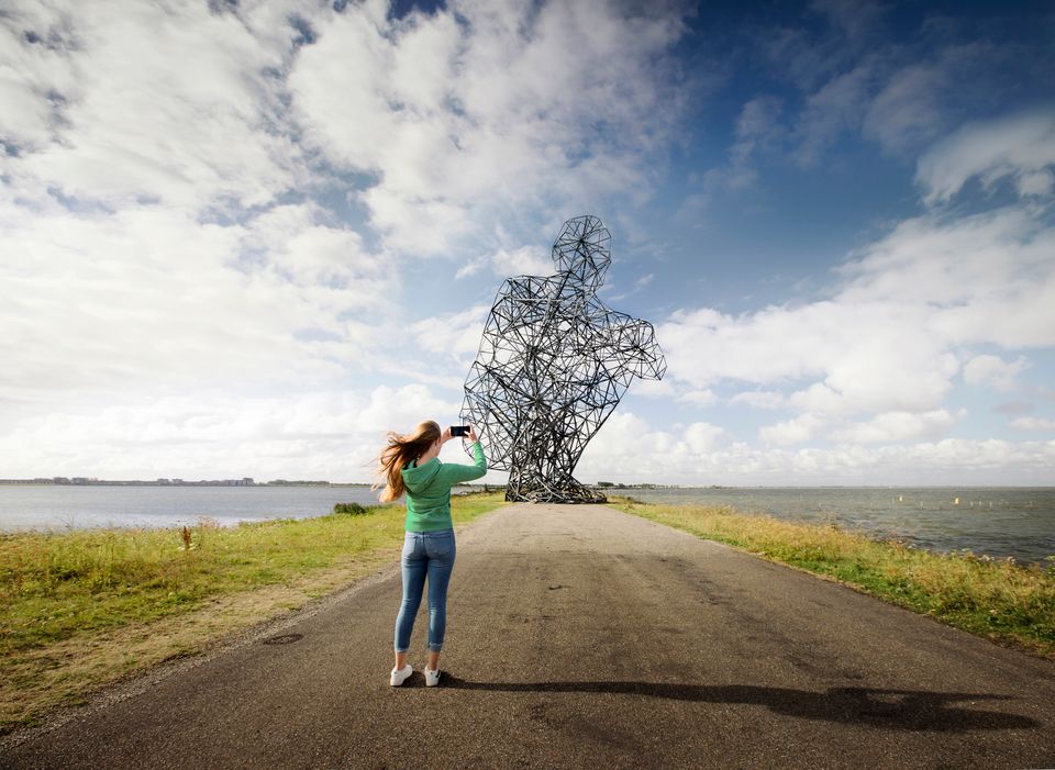 Een vrouw fotografeert Exposure, land art in het landschap van Lelystad, Flevoland