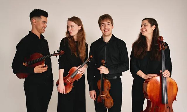 twee vrouwen en twee mannnen met violen en een cello poseren tegen een witte achtergrond.